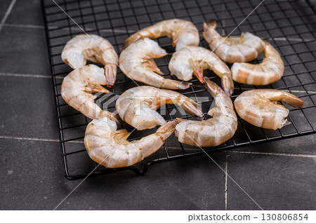 Raw shrimps, headless fresh prawns on a rack. Top view. Black background Raw shrimps, headless fresh prawns on a rack. Top view. Black background 130806854
