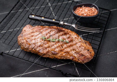 Grilled Striploin steak, New York strip beef meat steak on a rack. black background. top view 130806864