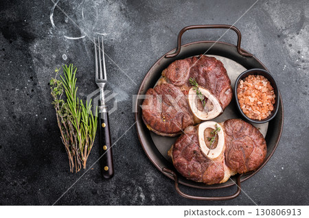 Deliciously braised ossobuco, featuring tender osso buco veal shank and rich marrow, perfect for a gourmet Italian feast. black background. top view 130806913