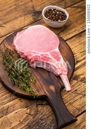 Pristine pork loin chop, featuring a thick cut and beautiful marbling, ideal for a hearty dinner. wooden background. top view Pristine pork loin chop, featuring a thick cut and beautiful marbling, ideal for a hearty dinner. wooden background. top view 130806922