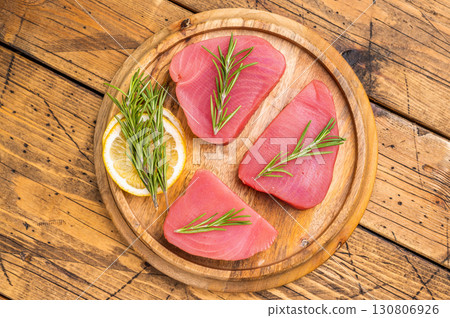 High quality raw tuna steak loin, perfect for a refreshing poke bowl or a delicious seared dish that impresses every time. wooden background. top view High quality raw tuna steak loin, perfect for a refreshing poke bowl or a delicious seared dish that impresses every time. wooden background. top view 130806926