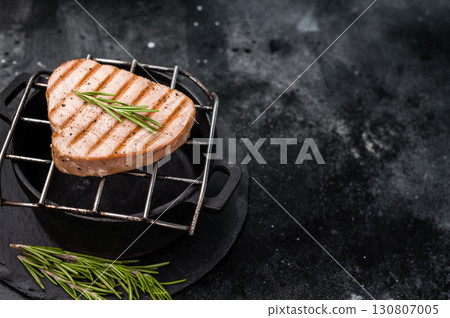 Juicy grilled tuna steak, perfectly seared with a smoky flavor, ideal for seafood lovers and gourmet dishes. black background. top view Juicy grilled tuna steak, perfectly seared with a smoky flavor, ideal for seafood lovers and gourmet dishes. black background. top view 130807005