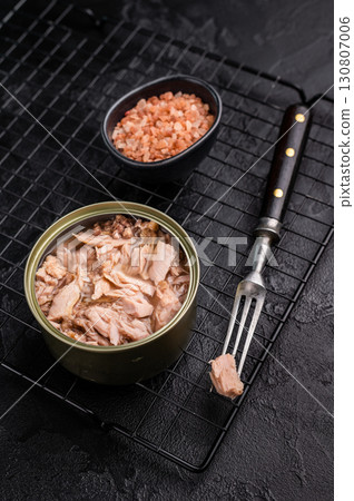 Convenient tinned tuna fillet, perfect for quick meals and packed with protein for a healthy lifestyle. black background. top view Convenient tinned tuna fillet, perfect for quick meals and packed with protein for a healthy lifestyle. black background. top view 130807006
