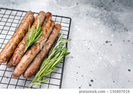 Flavorful grilled sausage links on a rack, inviting you to enjoy a hearty meal with family and friends. grey background. top view Flavorful grilled sausage links on a rack, inviting you to enjoy a hearty meal with family and friends. grey background. top view 130807016