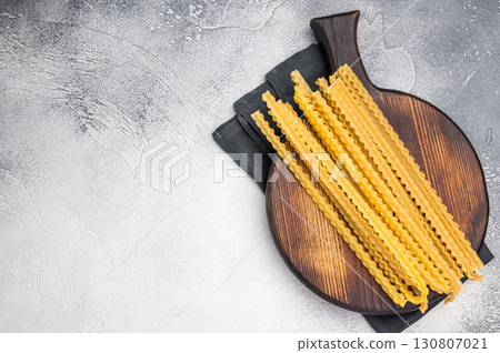Delicate raw mafaldine pasta noodles, perfect for tossing with fresh ingredients and savory sauces. white background. top view 130807021