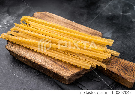 Uncooked mafaldine, ready to be transformed into a delicious dish that highlights its delightful texture. black background. top view 130807042