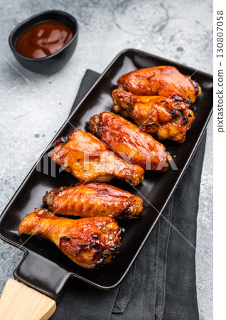 Juicy barbecue chicken wings, perfectly grilled and glazed, ideal for your next summer cookout or party. grey background. top view Juicy barbecue chicken wings, perfectly grilled and glazed, ideal for your next summer cookout or party. grey background. top view 130807058