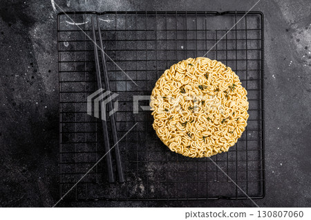 Raw instant ramen noodles, perfectly twisted and ready to be boiled for a delicious homemade soup. black background. top view Raw instant ramen noodles, perfectly twisted and ready to be boiled for a delicious homemade soup. black background. top view 130807060