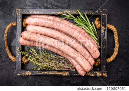 Raw sausage packed with herbs and spices, inviting you to create mouthwatering dishes for any occasion. black background. top view Raw sausage packed with herbs and spices, inviting you to create mouthwatering dishes for any occasion. black background. top view 130807061