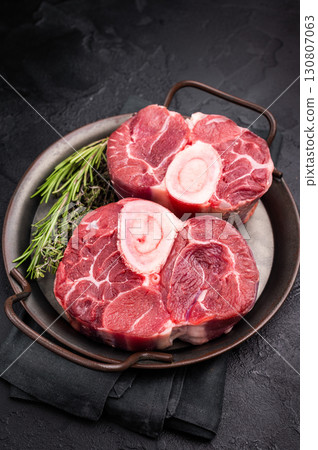 Freshly cross cut shank osso buco, ossobuco meat featuring succulent meat and bone marrow, waiting to elevate your cooking experience. black background. top view 130807063