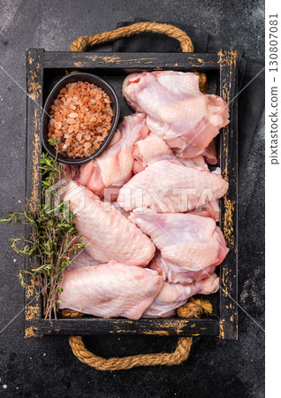 Beautifully arranged raw chicken wings, ready to soak up your favorite marinades for a tasty culinary adventure. black background. top view Beautifully arranged raw chicken wings, ready to soak up your favorite marinades for a tasty culinary adventure. black background. top view 130807081