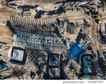 Aerial view of an active construction site in Riga, Latvia, featuring a steel framework, workers, machinery, and materials for the Southern Bridge project. Aerial view of an active construction site in Riga, Latvia, featuring a steel framework, workers, machinery, and materials for the Southern Bridge project. 130807447