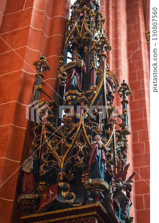 Intricately detailed Gothic altar or pulpit with gold accents, colorful statues of saints and angels, and red brick columns in a Frankfurt church. Intricately detailed Gothic altar or pulpit with gold accents, colorful statues of saints and angels, and red brick columns in a Frankfurt church. 130807560