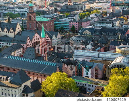 Aerial image of Frankfurt, Germany, featuring the Romer, St. Nicholas Church, colorful facades, modern buildings, and greenery in the foreground. Aerial image of Frankfurt, Germany, featuring the Romer, St. Nicholas Church, colorful facades, modern buildings, and greenery in the foreground. 130807629