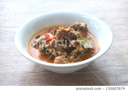 spicy boiled slice beef with lemon leaf in coconut milk red curry soup on bowl 130807674