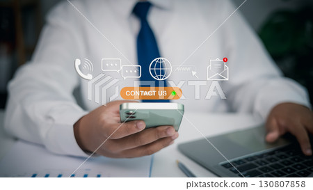 Businessman using smartphone with contact us button and digital communication icons 130807858