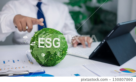 Businessman working on ESG sustainability concept with green globe and environmental icons Businessman working on ESG sustainability concept with green globe and environmental icons 130807860