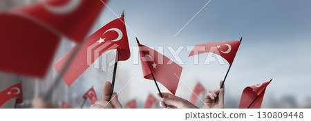 Turkey flags in their hands on a blurred urban background 130809448