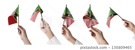 The Saint Kitts and Nevis flag in hand in different angles on a white background 130809465