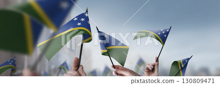 Solomon flags in their hands on a blurred urban background Solomon flags in their hands on a blurred urban background 130809471