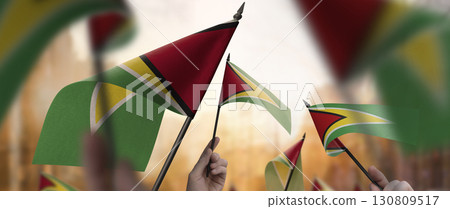 Guyana flags in their hands on a blurred urban background 130809517