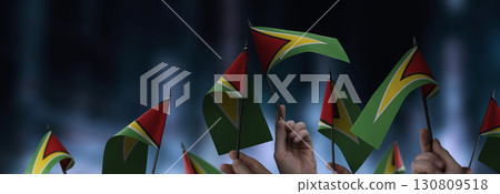 Guyana flags in their hands on a blurred urban background 130809518
