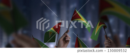 Guyana flags in their hands on a blurred urban background 130809532