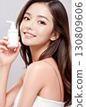 拿著化妝品瓶的年輕女子 130809606