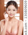 拿著化妝品瓶的年輕女子 130809609