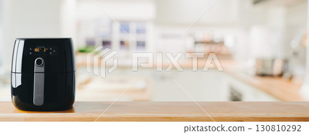 Digital air fryer machine on wooden table in home kitchen 130810292