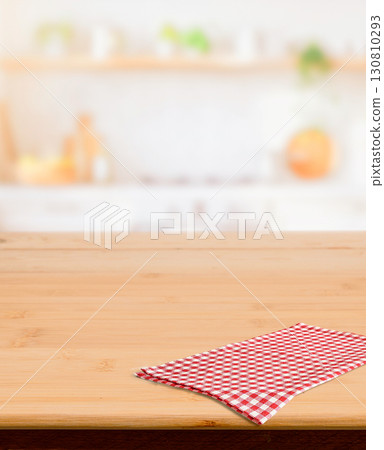Wooden surface with checkered cloth and blurred home kitchen interior 130810293