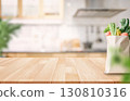 Fresh groceries in paper bag on wooden countertop with kitchen background 130810316