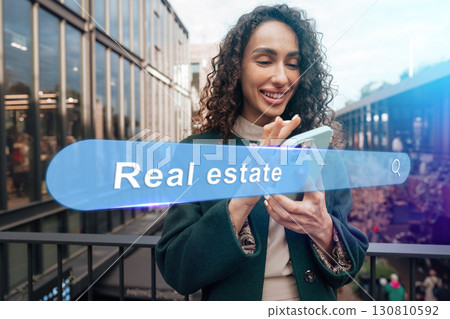 Young woman browsing real estate listings on smartphone at modern urban location during daytime Young woman browsing real estate listings on smartphone at modern urban location during daytime 130810592