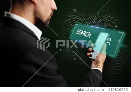 Man in a suit using smartphone to conduct a search on a glowing touchscreen at a dark background 130810633