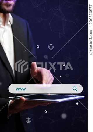 Business professional interacts with digital tablet in dark space representing online search 130810677