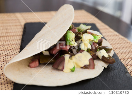 salad of black tomatoes, avocado and onions in Italian tortilla on black stone board salad of black tomatoes, avocado and onions in Italian tortilla on black stone board 130810780