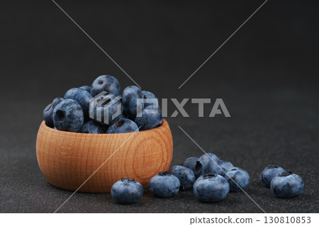 Fresh ripe blueberries in wooden bowl on dark gray stone background closeup macro healthy food Fresh ripe blueberries in wooden bowl on dark gray stone background closeup macro healthy food 130810853