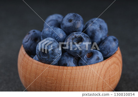 Fresh ripe blueberries in wooden bowl on dark gray stone background closeup macro healthy food 130810854
