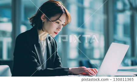 A young businesswoman concentrating on her work in a bright office 130811365
