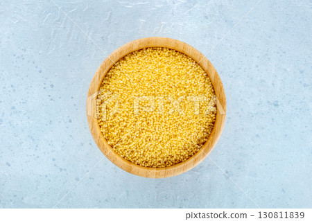 Millet, ancient African grain, in a wooden bowl on a blue background 130811839