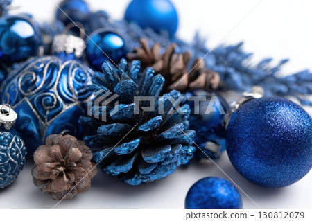 Blue Christmas decorations on a white background, blue Christmas tree branches and ornaments. Christmas-themed fir branches, glitter balls, baubles and pine cones. New Year garland decoration. 130812079