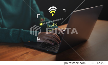 Person using a laptop computer with slow internet connection icon and loading screen interface. Concept of technology delay, network issues, data buffering and low Wi-Fi signal during online activity. 130812350