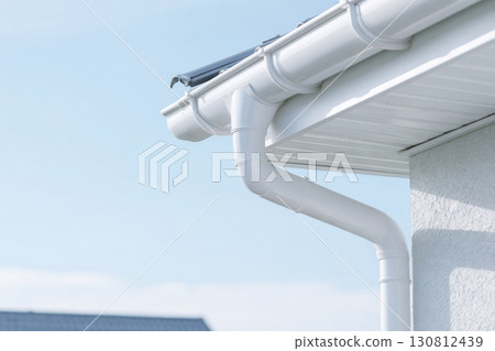 Contemporary Gutter Installed on a Residential House Roof to Enhance Functionality. Clean well maintained rain gutter system. Roof architecture effectively. Polymer storm drainage. Home architectural 130812439