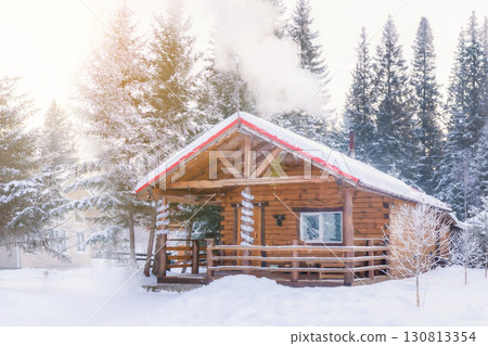 Russian wooden bathhouse in a snowy clearing in winter. Smoke is coming out of the bathroom chimney. 130813354