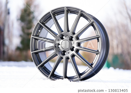 Premium alloy wheel showcasing sleek design and craftsmanship against a crisp outdoor backdrop in winter setting with snow 130813405