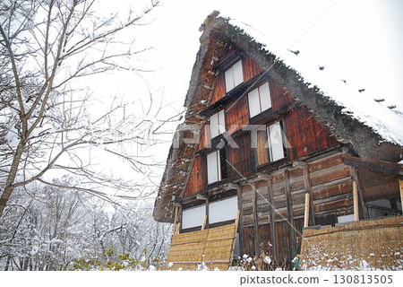 Snow-covered Shirakawa-go gassho-zukuri village, travelers walking through a silvery white world and the historic townscape 130813505