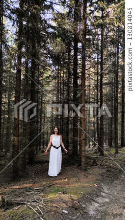 Woman wearing white dress walking in coniferous forest in vsechlapy, czechia Trail of the Knight 130814045