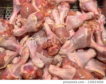 A close-up, full-frame shot of a large pile of fresh, raw chicken drumsticks on a meat counter display at a grocery store. A close-up, full-frame shot of a large pile of fresh, raw chicken drumsticks on a meat counter display at a grocery store. 130814088
