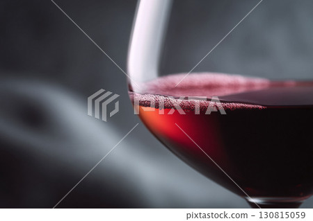 Closeup of a filled wine glass with red liquid against a gray backdrop. Evokes sophistication, indulgence, and celebration. Suitable for food, drink, and lifestyle content. 130815059