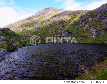 Serene mountain lake scene. Golden light highlights rugged slopes, creating a stunning natural masterpiece. Serene mountain lake scene. Golden light highlights rugged slopes, creating a stunning natural masterpiece. 130816571